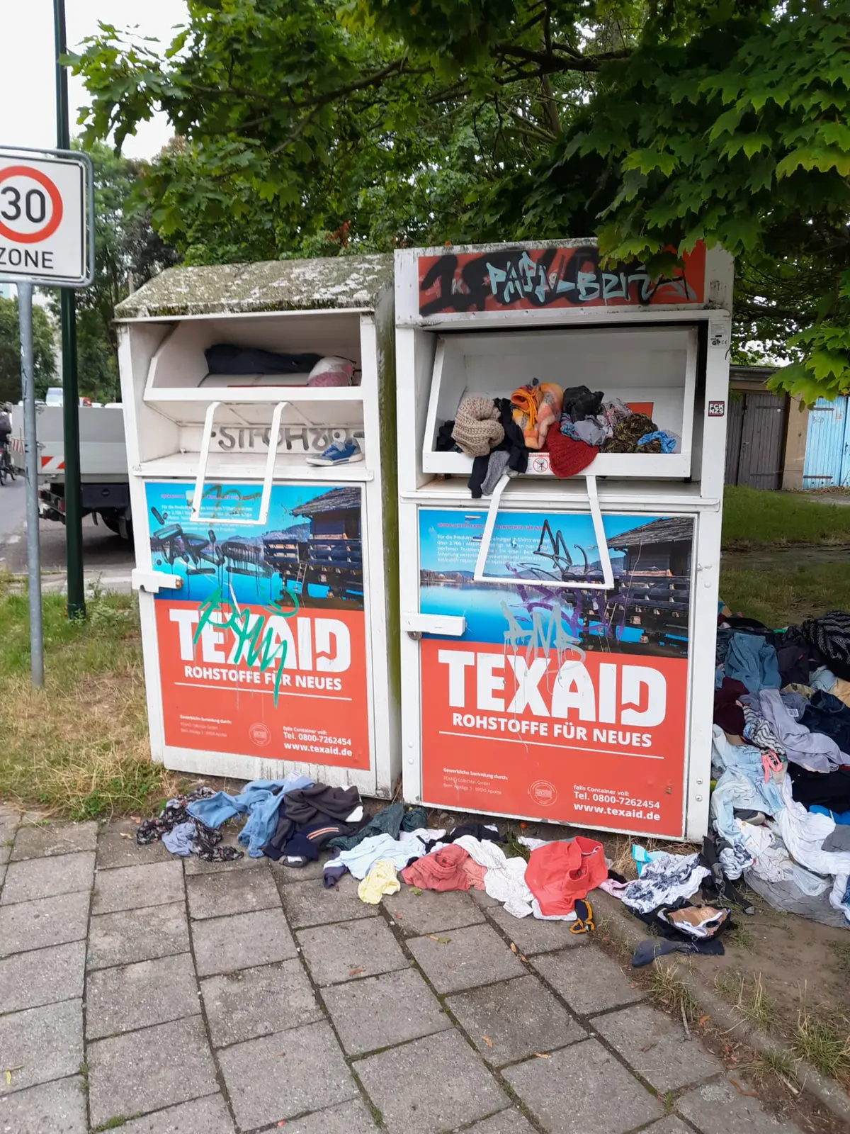Zwei Altkleidercontainer sind überfüllt.