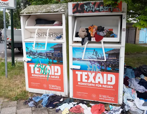 Zwei Altkleidercontainer sind überfüllt.
