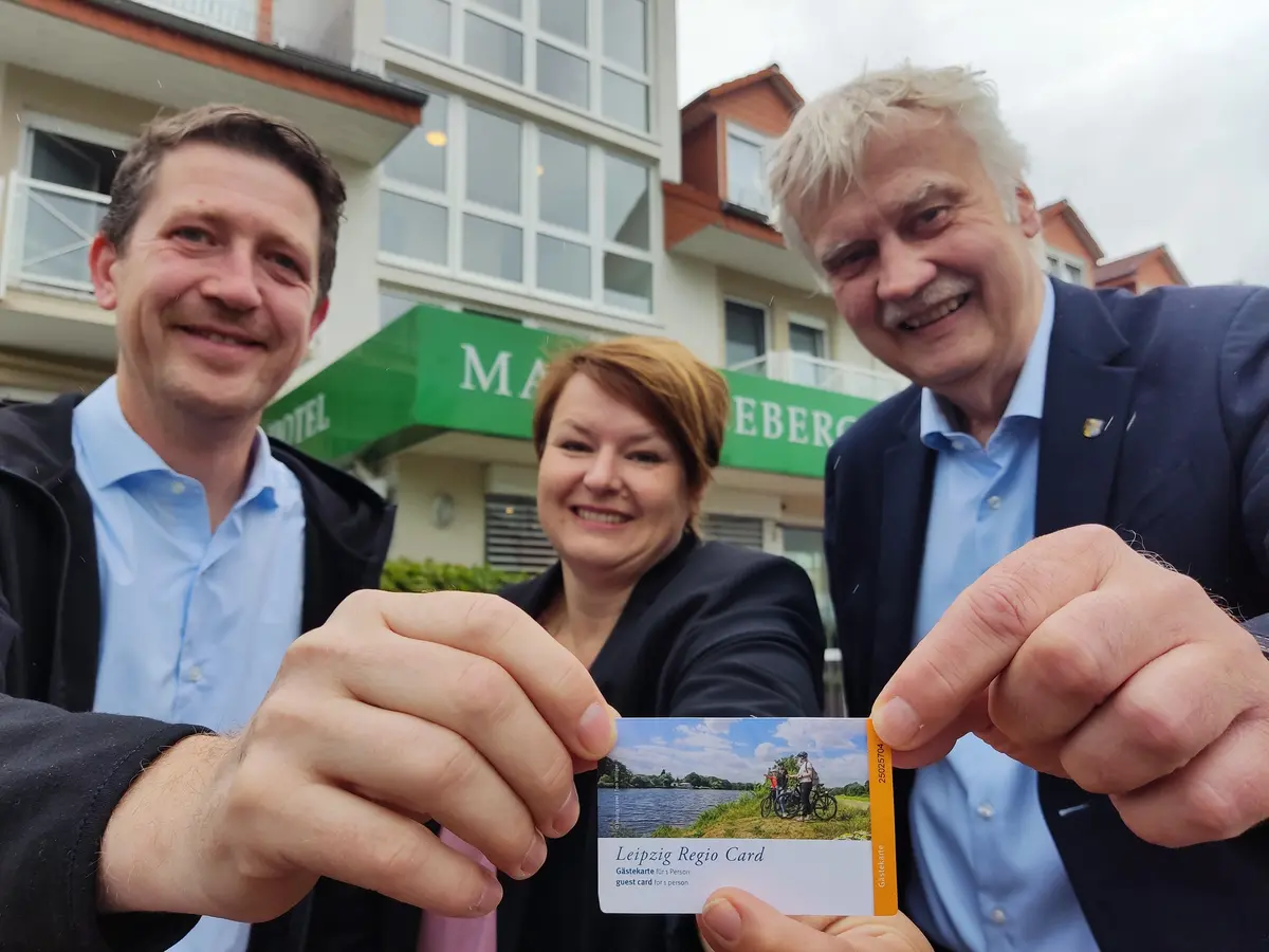 Drei Personen halten Karte - die Gästekarte.