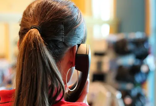 Eine Frau hält einen Telefonhörer ans Ohr.