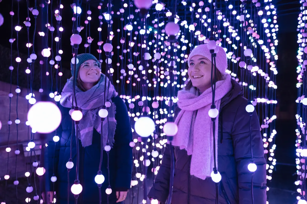 Zwei Personen stehen inmitten einer Lichtinstallation und freuen sich.