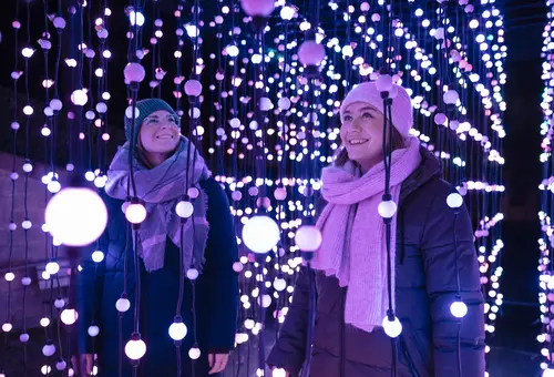 Zwei Personen stehen inmitten einer Lichtinstallation und freuen sich.