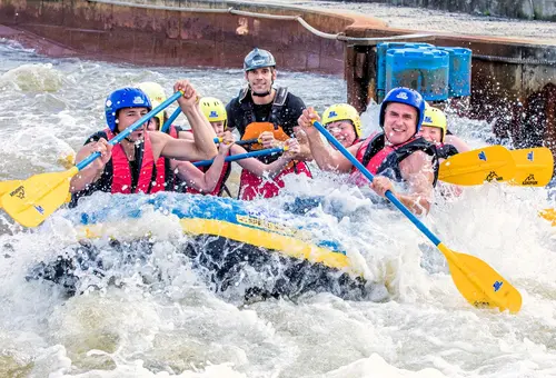 Menschen sitzen in einem Raftingboot und haben Spaß.